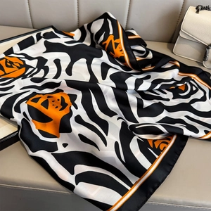 Zijdeachtige sjaal met oranje en zwarte tijgerprint op grijs lederen oppervlak
