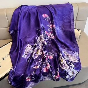 Élégant foulard en soie violette avec de grands motifs floraux sur un canapé