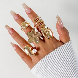 Detailansicht von fünf goldenen Vintage-Ringen mit Perlen und Blumenmotiven an der Hand