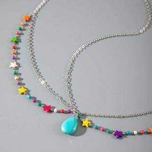 Gros plan d'un bijou de tête bohème avec perles colorées, étoiles et pendentif turquoise