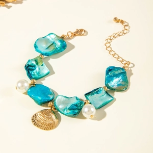 Detail of blue shell bracelet with gold scallop pendant and white pearl accents