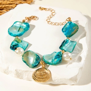 Detail of gold ocean bracelet with blue shell slices, faux pearls and shell pendant