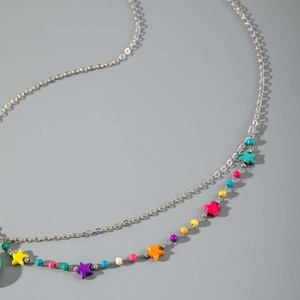 Vue macro d'une chaîne argentée double couche avec perles colorées et pendentifs étoiles