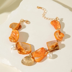 Close-up of ocean-style beaded bracelet with shell pieces, pearls and a golden scallop charm