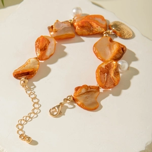 Detail of starfish bracelet with orange shell pieces, white pearls and gold shell pendant