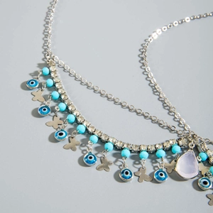 Détail de la chaîne de tête argentée avec charms œil maléfique et pendentif goutte violette