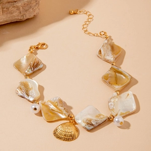 Macro detail of gold-plated ocean-style bracelet with seashell, pearl and scallop charm
