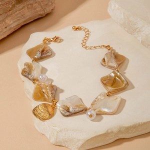 Close-up of ocean-style bracelet with iridescent shells, pearls and golden scallop charm