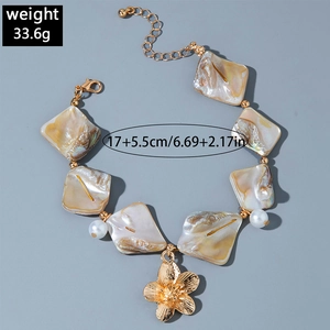 Detailed view of ocean style gold bracelet with shell tiles, pearls and flower pendant