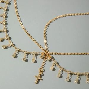 Détail d'une chaîne de tête bohème dorée avec zircons brillants et pendentif en croix