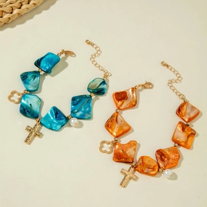 Detail of beaded shell bracelets with cross and pearl charms in blue and orange