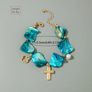 Detail of blue shell bracelet with gold cross pendant, pearl, and 25.6g weight label
