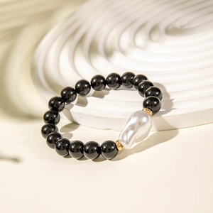 Minimalist black beaded bracelet with a large white baroque pearl on a wavy tray