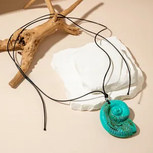 Makroaufnahme des blaugrünen Nautilus-Anhängers mit dunklen Texturen an schwarzer Kordel