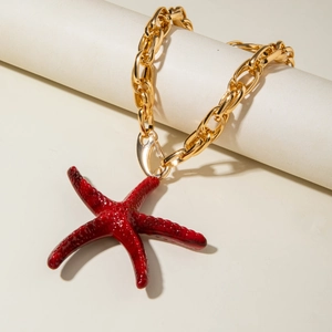 Détail d'un collier à grosse chaîne dorée avec un pendentif étoile de mer rouge