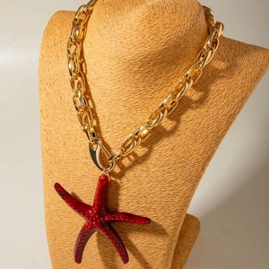 Detail einer großen roten Seestern-Halskette an einer dicken Goldkette für den Strandurlaub