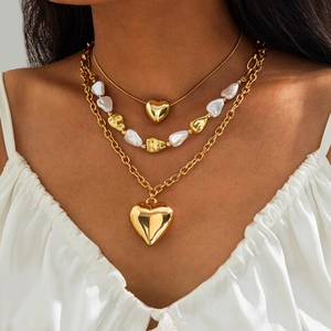 Detalle del collar de capas con perlas barrocas y colgantes de corazón dorado en modelo