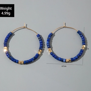 Détail de grandes créoles avec perles bleues texturées et accents en métal doré