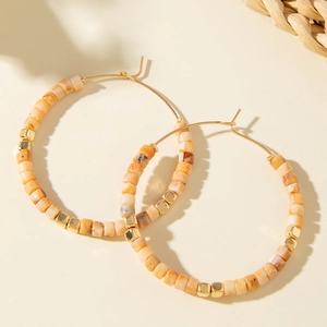 Gros plan sur les perles de résine orange et cubes dorés de ces boucles d'oreilles