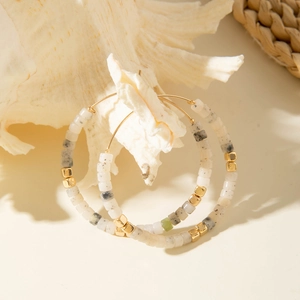 Détail de boucles d'oreilles créoles avec perles en résine sur un coquillage