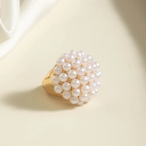 Close-up of golden ring featuring a cluster of white pearls against a silk fabric