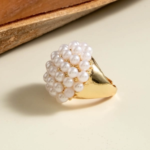 Detailed view of cluster pearl ring with gold metal band on elegant beige surface