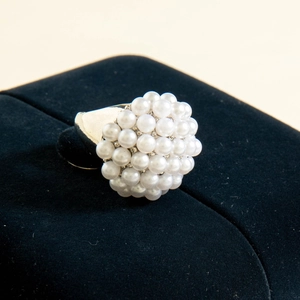 Detailed view of cluster pearl ring with white beads on silver metal band on velvet