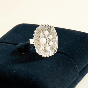 Detailed shot of irregular silver scallop ring with pearls on blue velvet case