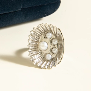 Detail of silver shell-shaped ring featuring textured relief and five white pearls
