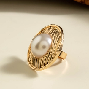 Detailed view of a vintage gold ring featuring a large oval pearl and textured rays
