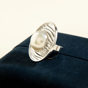 Macro shot of silver pearl ring with radiant texture on blue velvet jewelry box