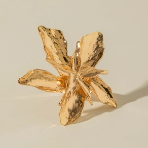 Close-up of golden floral ring with irregular texture and high-gloss metallic finish