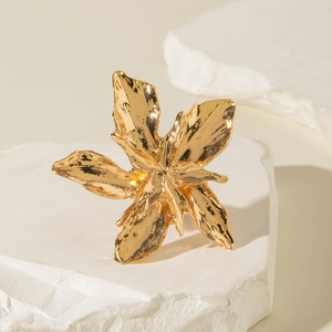 Detailed close-up of golden irregular flower ring with hand-hammered texture on white stone