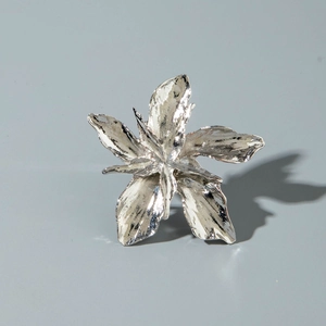 Detailed close-up of a silver floral ring with five-petal blossom and realistic metal texture