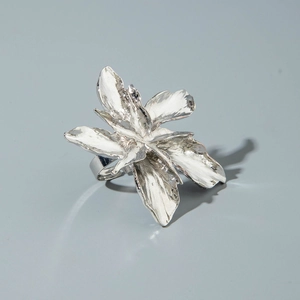 Detailed view of silver flower ring with irregular lava texture and metallic petals