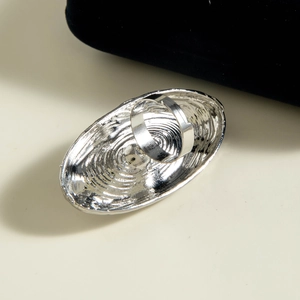 Macro shot of silver oversized oval ring featuring ripple textures and smooth metal band