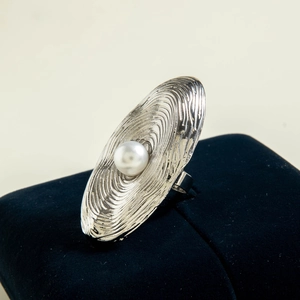 Detailed view of silver oval ripple ring with a central white pearl on navy velvet