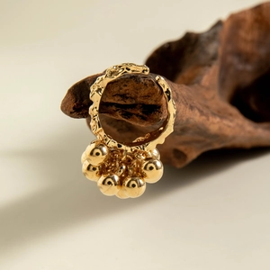 Close-up of golden irregular textured open ring with multiple dangling polished beads