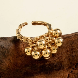 Detail of adjustable gold spiral ring with hammered texture and hanging metallic beads