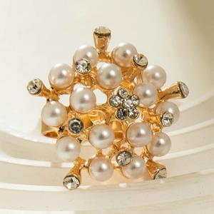 Detailed shot of golden flower spiral ring with pearls and rhinestones on geometric base