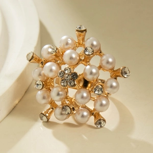 Detailed view of vintage gold ring with floral pearls and crystals on beige base