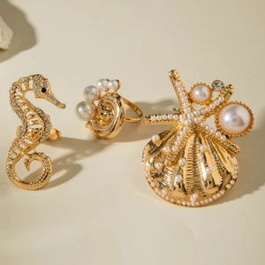 Macro detail of golden sea horse and starfish rings with pearls and crystals