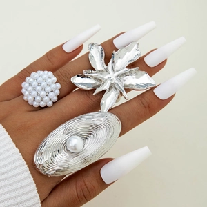 Three-piece silver ring set with oversized pearls and metallic floral designs on hand