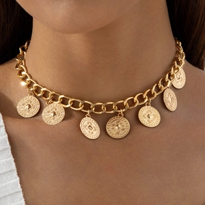 Gros plan sur un collier à maillons cubains dorés à plusieurs rangs et pendentifs pièces