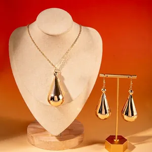 Elegant gold teardrop jewelry set with necklace and earrings on a premium display stand