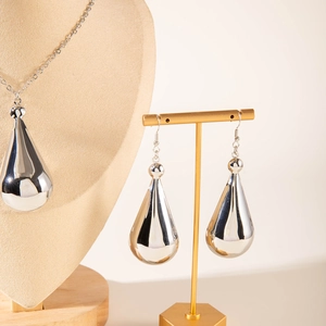 Close-up of silver teardrop necklace and earrings set on high-quality display stands