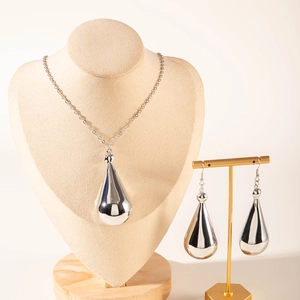 Close-up of teardrop necklace and earrings set on a jewelry display stand with mirror finish
