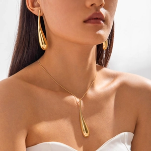 Close-up of gold teardrop necklace and matching earrings set with polished finish
