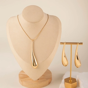 Close-up of golden teardrop necklace and earrings set on minimalist jewelry display