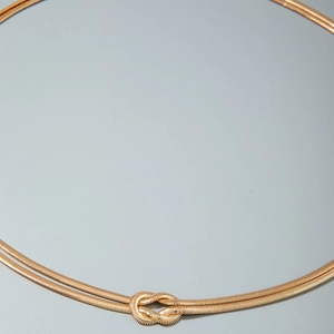 Dettaglio della catena da vita dorata a doppio filo con elegante nodo decorativo centrale